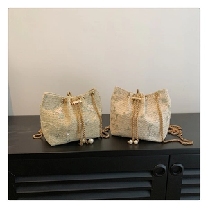 Detail of woven straw bucket bags with floral embroidery, gold chains and pearl tassels