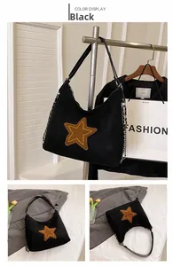 Detail view of the black frosted suede tote bag featuring a brown star patch and metal chain strap