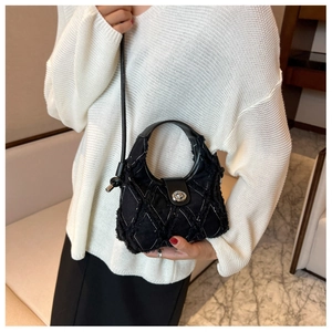 Détail du sac seau en toile matelassée noire avec bords effilochés et fermoir argenté