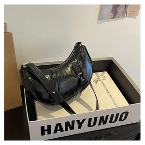 Detail of black pleated hobo bag with silver hardware and elegant gift packaging
