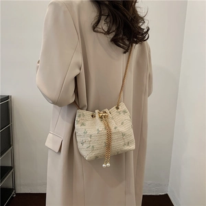 Chic beige woven straw bucket bag with green floral embroidery and gold chain strap
