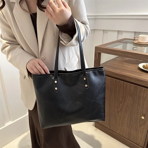 Minimalist black faux leather tote bag with long handles and gold rivet accents