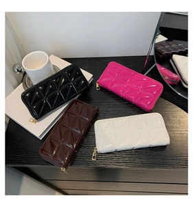Gros plan de portefeuilles en cuir verni matelassé noir, marron, rose et blanc avec zip doré