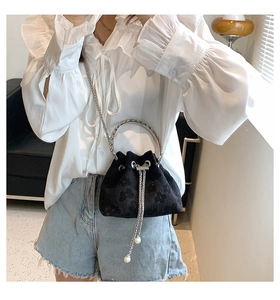Detail of black velvet bucket bag with 3D floral texture and pearl drawstring accents