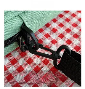 Close-up of light green canvas bag showing black zipper and plastic detachable hook details