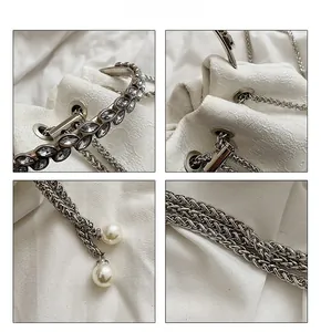 Detail of white fabric bucket bag with silver braided chain and pearl pendants