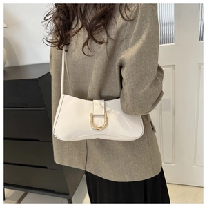 Close-up of minimalist beige baguette bag with a decorative gold D-ring buckle