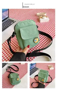 Detail view of a green canvas crossbody bag featuring a cute orange embroidery patch