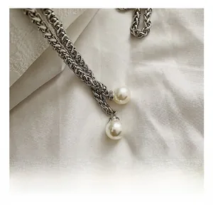 Detail of silver woven chain featuring twin pearls with sparkling crystal-inlaid bases