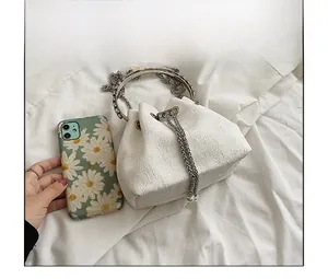 Mini white jacquard bucket bag detail showing size comparison with a smartphone