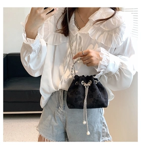 Detail of floral bucket bag featuring elegant silver tassels, pearls, and a metal ring handle
