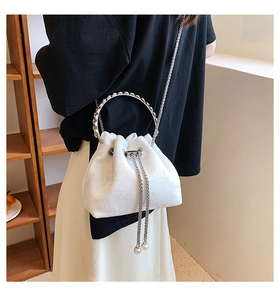 Detail of white drawstring bucket bag with floral texture and crystal ring handle