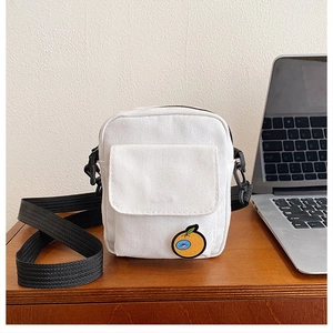 Detail view of white canvas crossbody bag featuring a cute orange cartoon embroidery patch