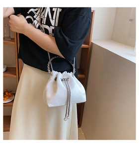 Detail of white jacquard bucket bag with silver metal ring handle and chain accents