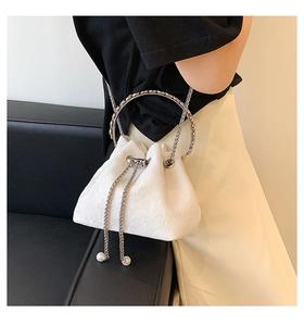 Detail of white bucket bag with floral embossing, metal chain drawstring and pearl accents