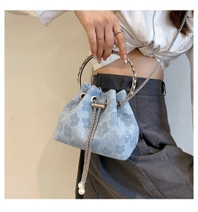 Detail of light blue drawstring bucket bag with floral patterns and pearl strap