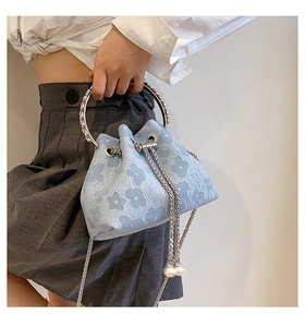 Detail of light blue bucket bag featuring floral jacquard fabric and silver metal ring handle