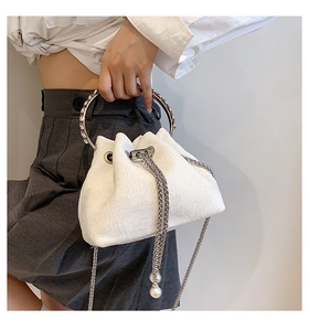 Detail of lace bucket bag with crystal metal handle and elegant pearl drawstring