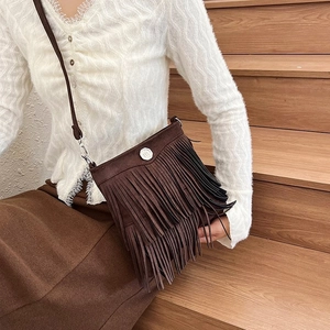 Chic dark brown tassel bucket bag in bohemian style with crossbody strap on a model