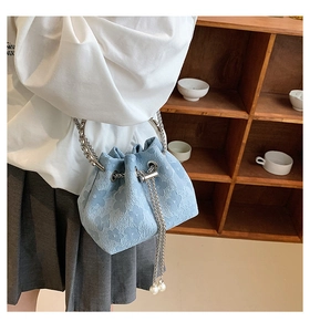 Close-up of light blue floral embossed bucket bag with silver handle and pearl chain