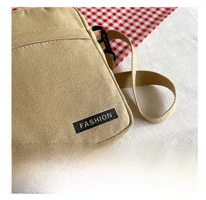 Detail shot of khaki canvas crossbody bag with a fashion woven label and zipper closure