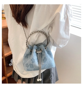 Close-up of light blue floral bucket bag with silver ring handle and pearl drawstring charms