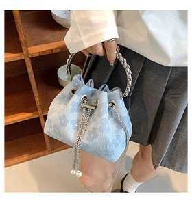 Detail of light blue jacquard bucket bag with floral relief texture and pearl chain strap
