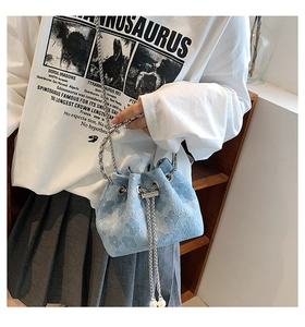 Detail of light blue floral embossed bucket bag with silver ring handle and pearl drawstrings