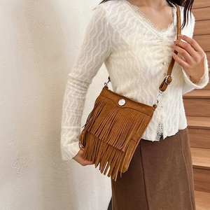Brown suede tassel bucket bag with bohemian fringe detail and metal button closure