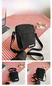 Detail view of black canvas crossbody bag with a fashion label and woven zipper puller