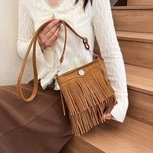 Detail view of brown suede bucket bag with long tassels and a round silver metal buckle