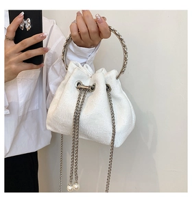 Detail of white bucket bag featuring floral embossed texture and pearl chain charms
