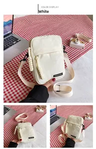 Detailed view of white canvas crossbody bag with black buckle and fashion label strap