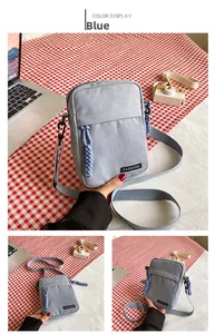Detail view of small blue canvas crossbody bag with fashion label and zipper puller cord