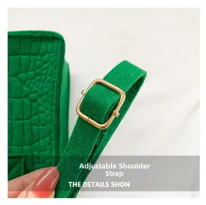 Close-up of adjustable strap with gold buckle and crocodile texture on green felt bag