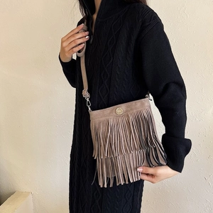 Detail of khaki suede fringe bucket bag with golden buckle and bohemian tassel layers