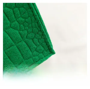 Close-up detail of green felt fabric with crocodile embossed texture and fine stitching