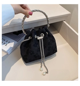 Macro detail of black jacquard bucket bag with silver ring handle and pearl drawstring charm