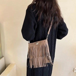 Brown suede tassel bucket bag shown on a model with tiered fringe and metal snap closure