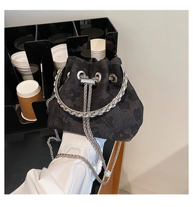 Detail of floral embossed bucket bag with rhinestone ring handle and silver chain strap