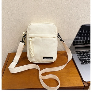 Detail of minimalist beige canvas crossbody bag with fashion label on wooden desk