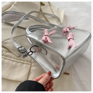 Détail du sac bandoulière argenté métallisé avec nœuds en cuir rose et bandoulière réglable