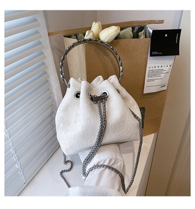 Detail of white lace embossed bucket bag with silver metal handle and chain strap