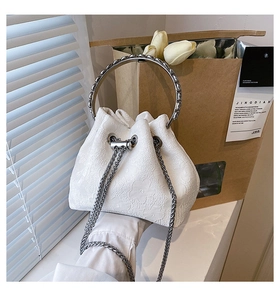 Detailed macro view of white floral jacquard fabric with metallic ring handle and chain