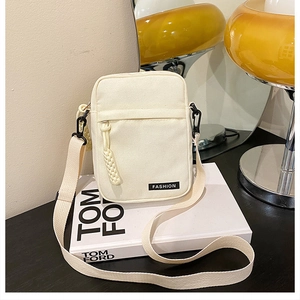 Detail view of cream canvas crossbody bag with black zipper and fashion label