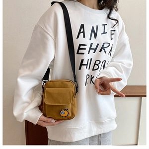 Detail of mustard yellow canvas crossbody bag featuring a cute cartoon character patch