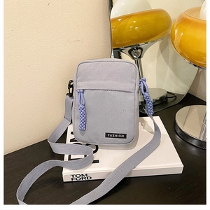 Detail view of mini canvas crossbody bag with fashion label and braided zipper pulls