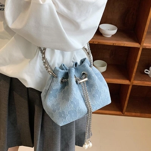 Light blue bucket bag with floral texture, metal ring handle, and pearl chain detail