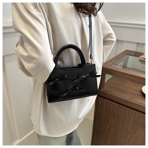 Détail d'un sac noir à nœuds montrant le design élégant des nœuds 3D et le similicuir