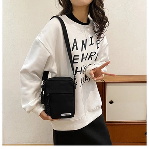 Close-up of black crossbody phone bag showing durable nylon texture and adjustable strap
